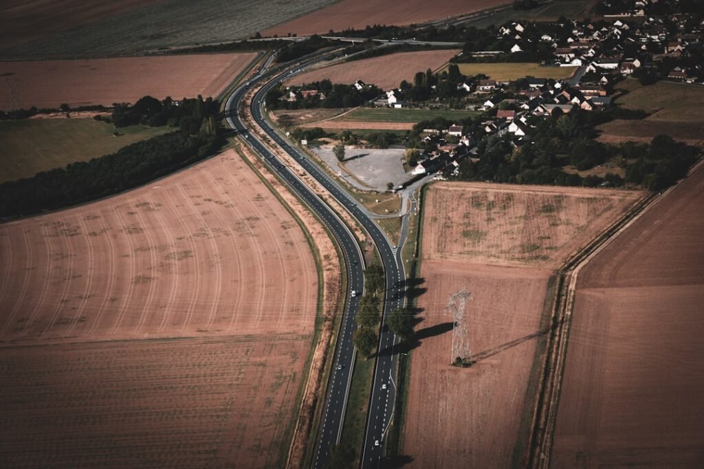 Aerial view of rural roads connecting small villages surrounded by agricultural fields, representing the decision-making process for choosing farmland corridors